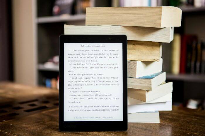 liseuse posée sur des livres papiers Liseuse : E Ink, Autonomie et Fonctionnement Expliqués
