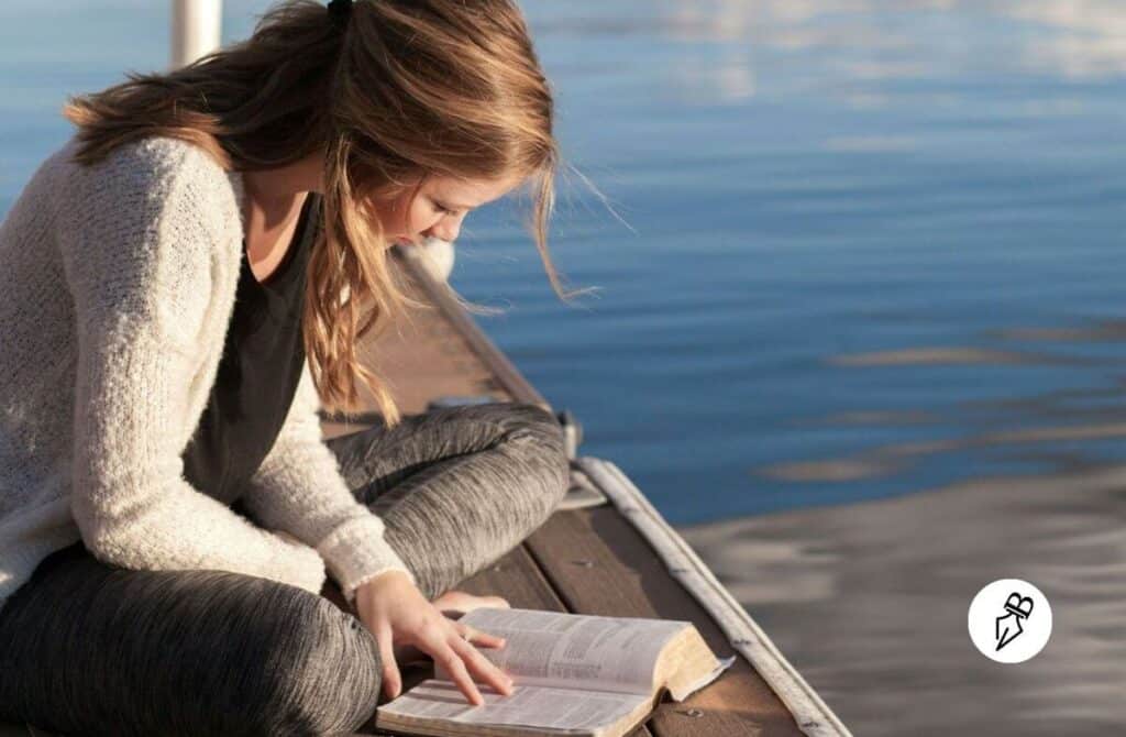 Partir en Livre 2026 : Célébrez vos héros préférés cet été ! Femme blonde assise qui lit un livre au bord d'un lac